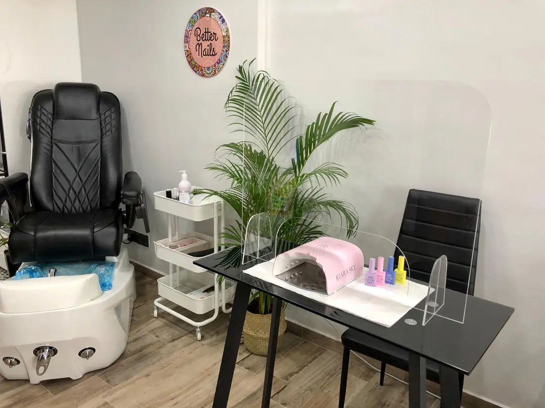The Better Nails studio: pedicure spa chair, manicure table with an acrylic screen, and a plant